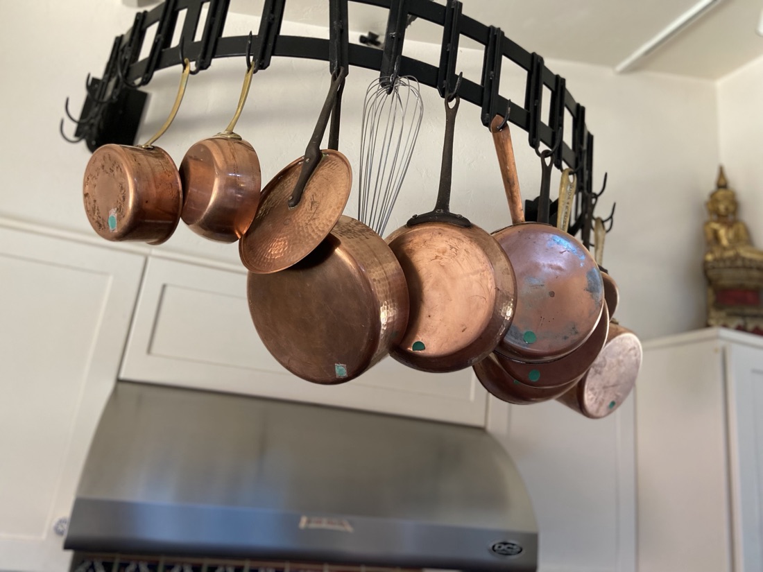 Copper pots and pans hanging from an iron pot rack in her kitchen