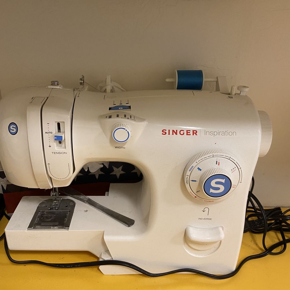 A white Singer sewing machine with a spool of blue thread